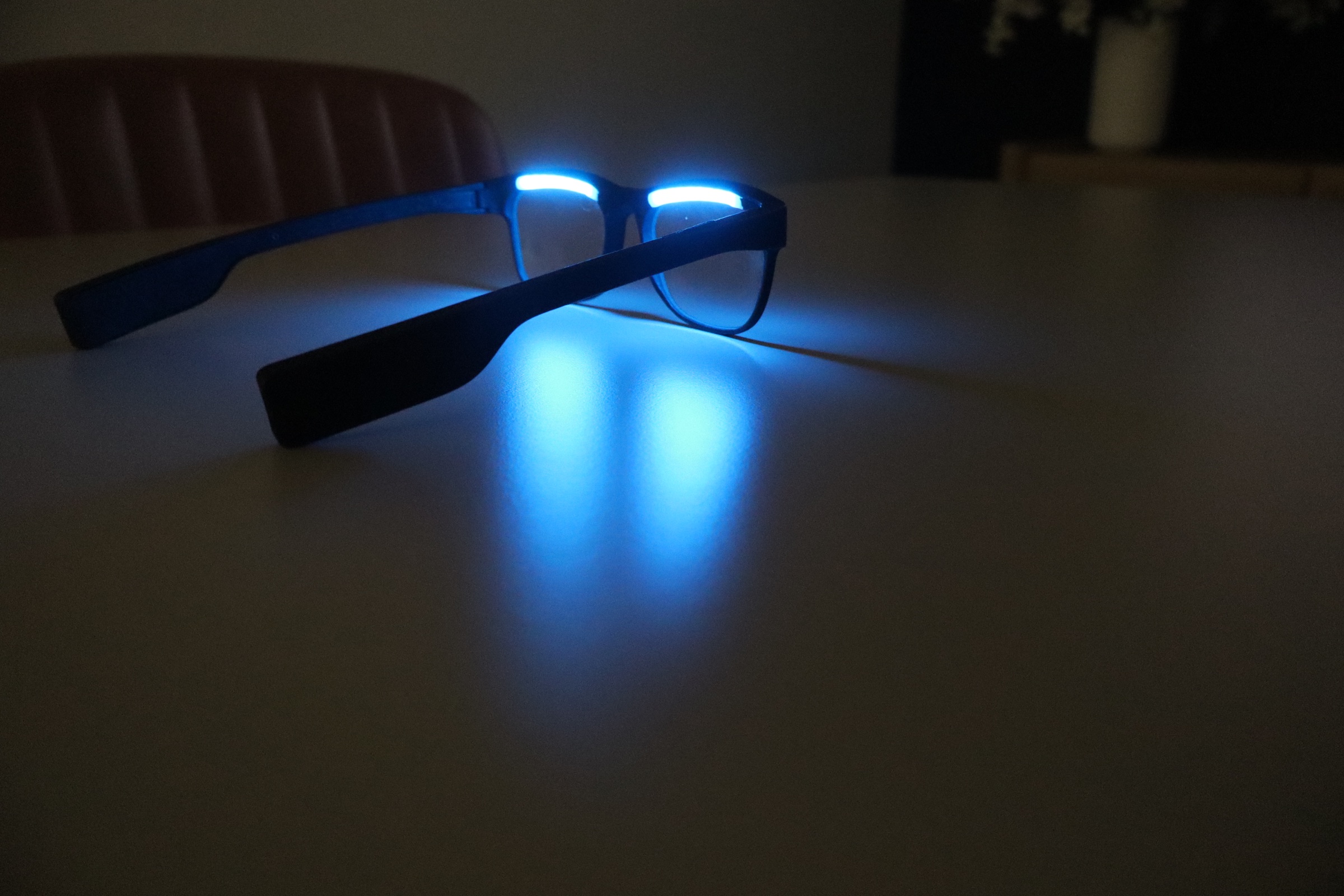 Side angle of a powered-on OptimRise engineering-validation prototype showing the upper-rim emitters and temples.