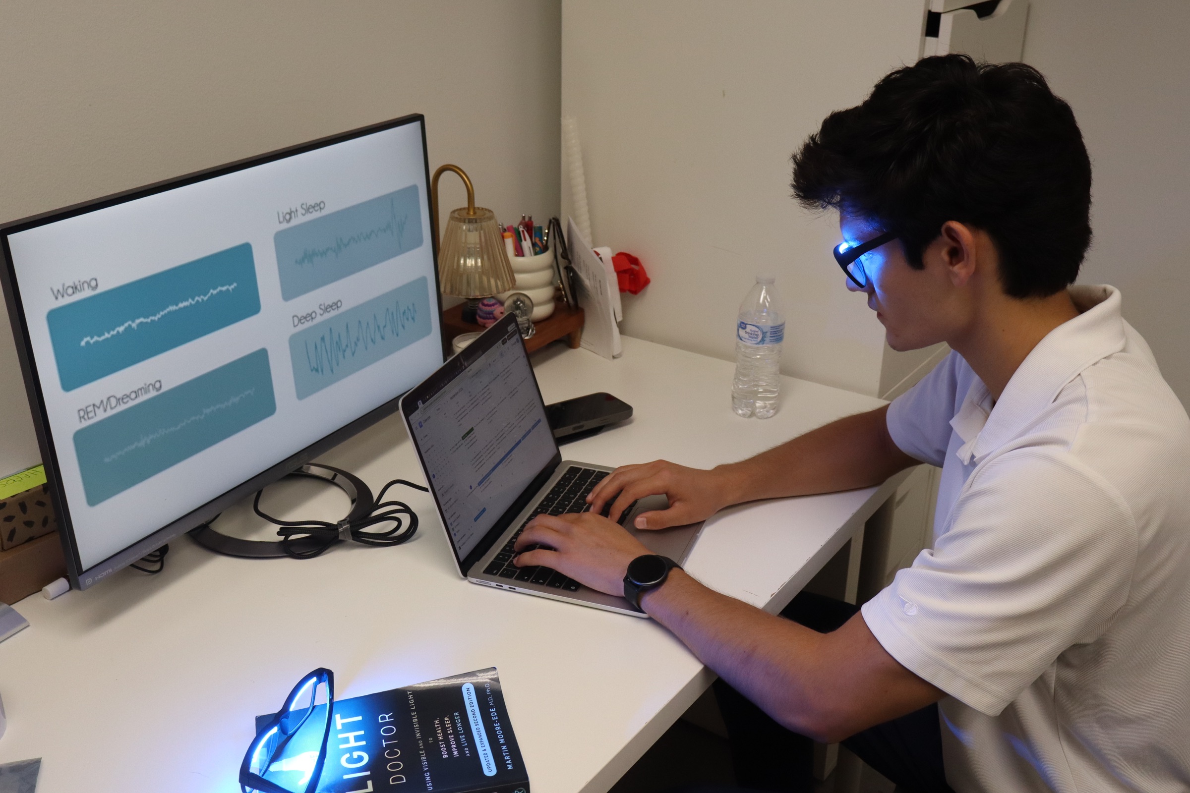 A person working at a desk while wearing a powered-on OptimRise engineering-validation prototype.